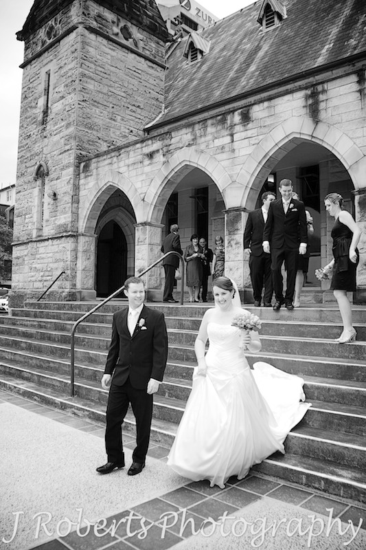 Bride and groom leaving the church followed by bridal party - wedding photography sydney